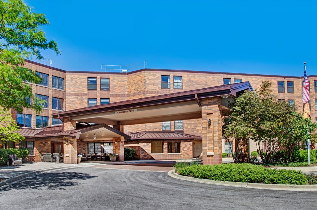 A hotel entrance with a covered driveway and landscaped surroundings.