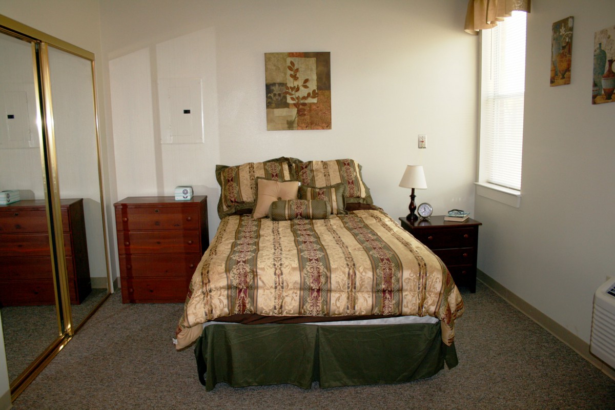 A cozy bedroom with a neatly made bed, nightstand, and artwork on the wall.