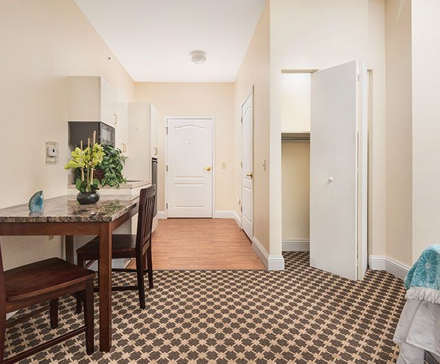 A modern apartment hallway featuring a dining area with a table, chairs, and decorative plants.