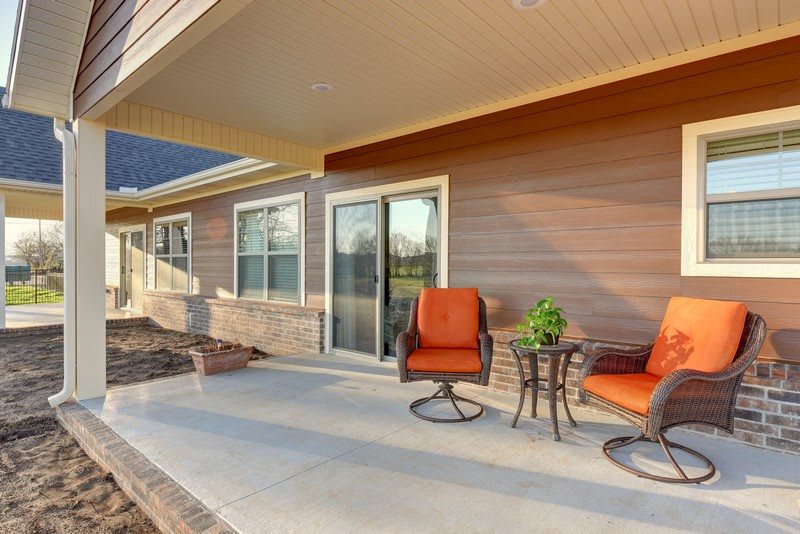 A cozy patio with orange cushioned chairs and a small table on a covered porch.