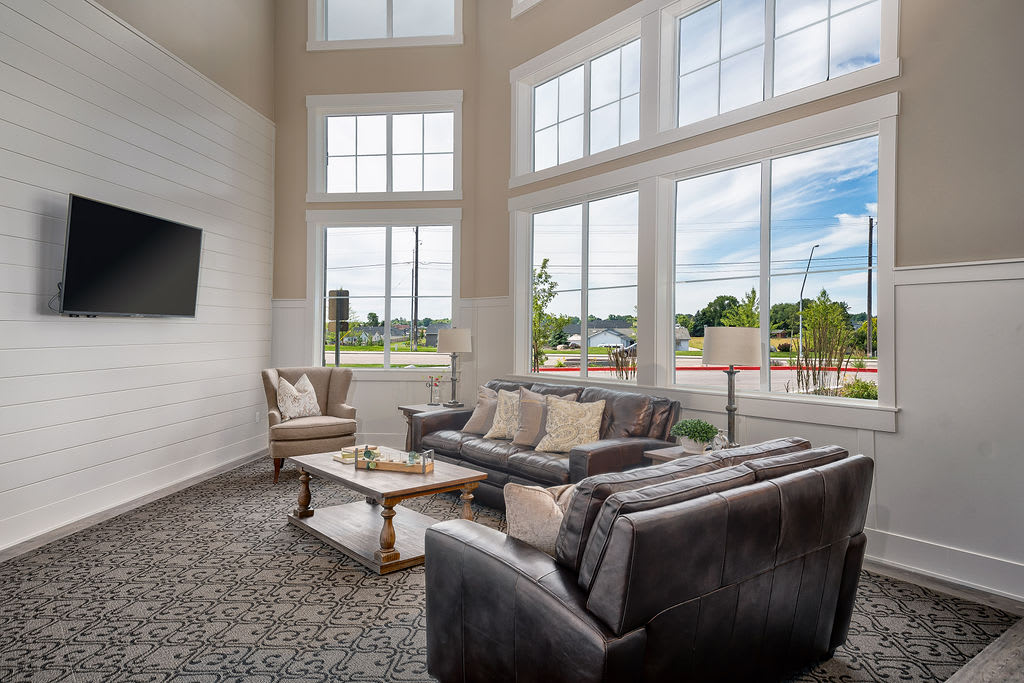 A spacious and modern living room filled with natural light, featuring large windows, comfortable sofas, a coffee table, and elegant decor.