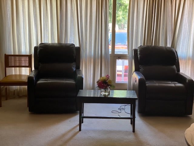A cozy living room with two chairs and a small table in front of a window with curtains.