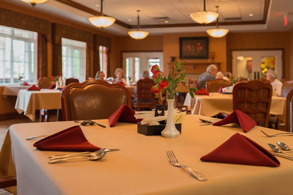 A cozy restaurant dining room with elegantly set tables and people in the background.