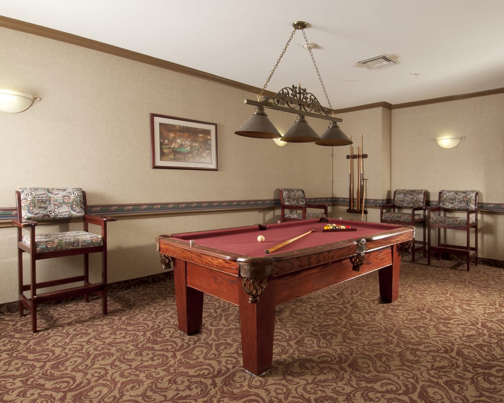 A recreation room featuring a pool table with overhead lighting and seating.
