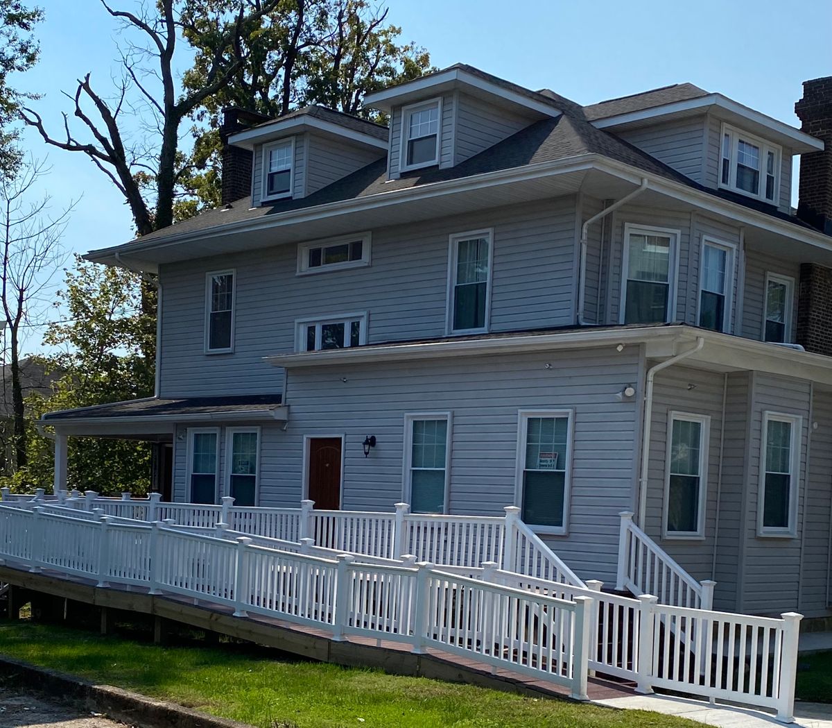 A three-story house with a white fence on a sunny day.