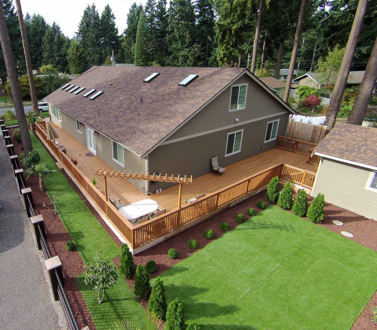 Aerial view of a suburban duplex with a large wooden deck and neatly maintained lawn.