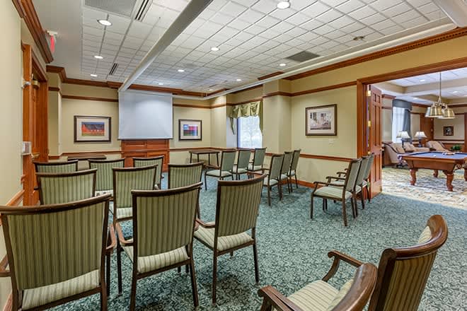 An empty conference room with arranged chairs and a projector screen ready for a meeting.