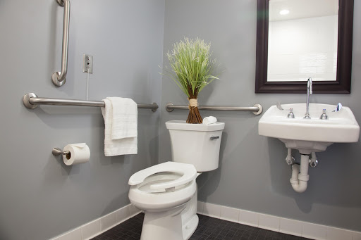 A modern bathroom featuring a toilet, sink, and decorative plant.