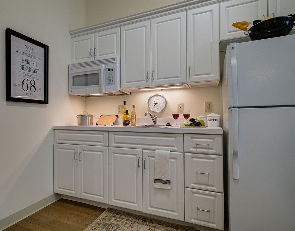 A modern kitchen with white cabinetry, a microwave, and a refrigerator.