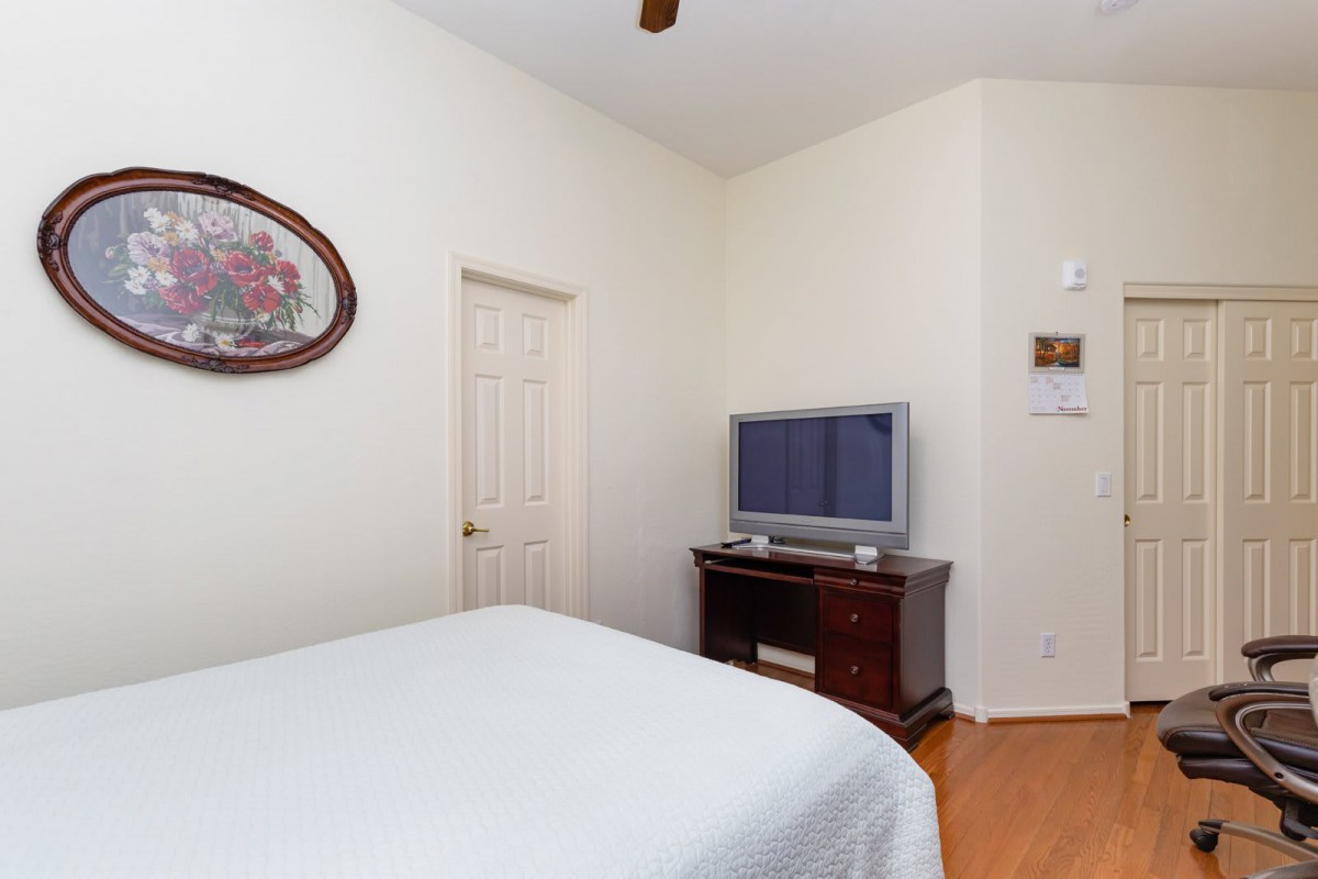 A cozy bedroom featuring a TV on a wooden stand and simple decor.