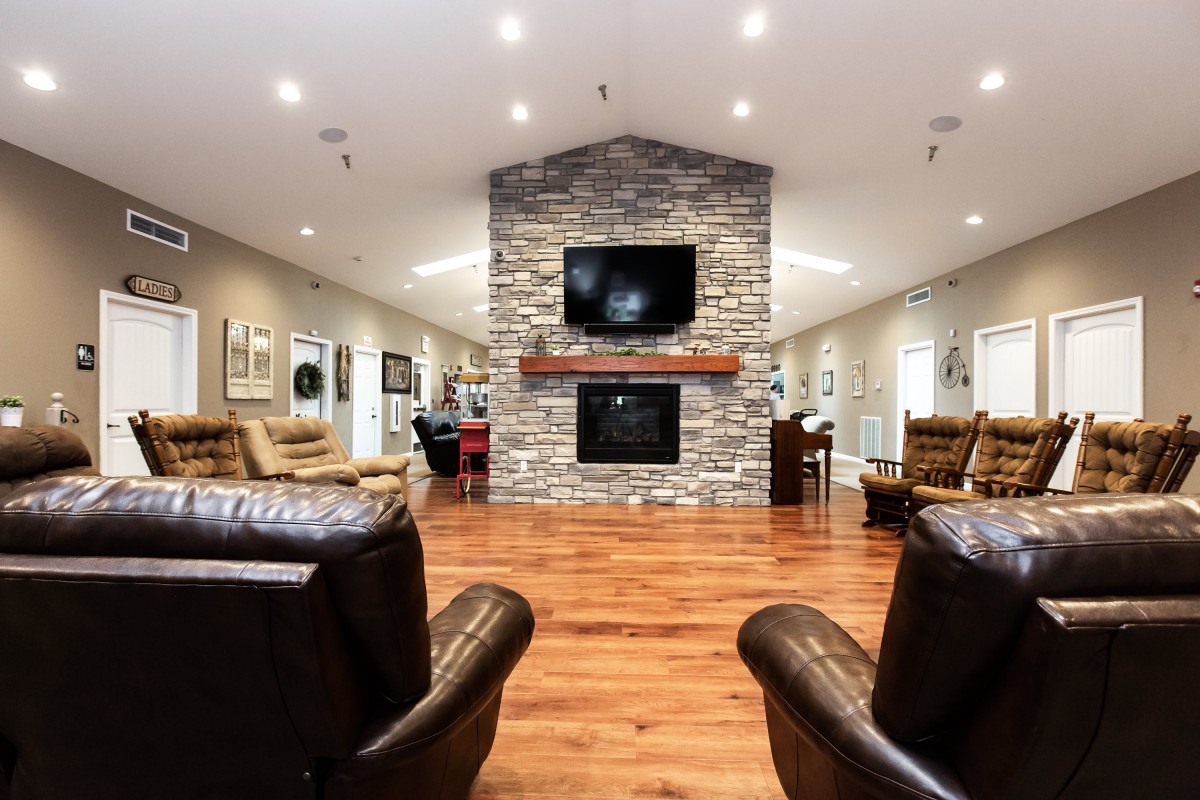 A cozy living room featuring a stone fireplace, hardwood floors, and comfortable leather seating.