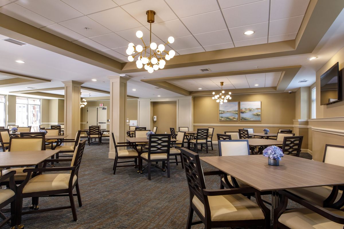 A spacious and elegantly designed dining room featuring multiple tables, chairs, and chandeliers.