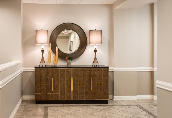 A modern interior featuring a console table with decorative items and lamps, complemented by a large round mirror.