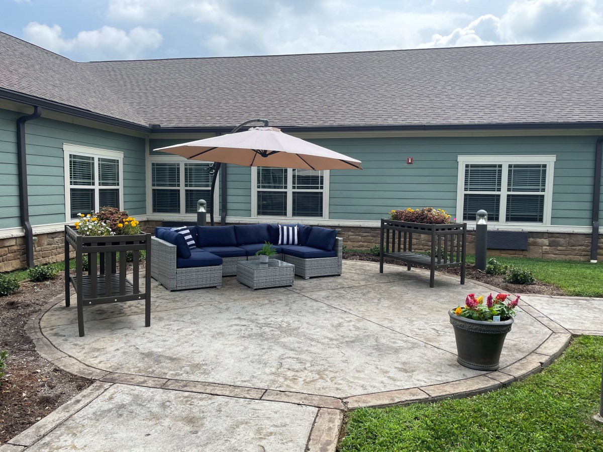 A cozy outdoor patio with seating and an umbrella in a garden setting.