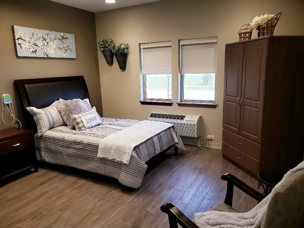 A cozy bedroom with a bed, armchair, and wardrobe.