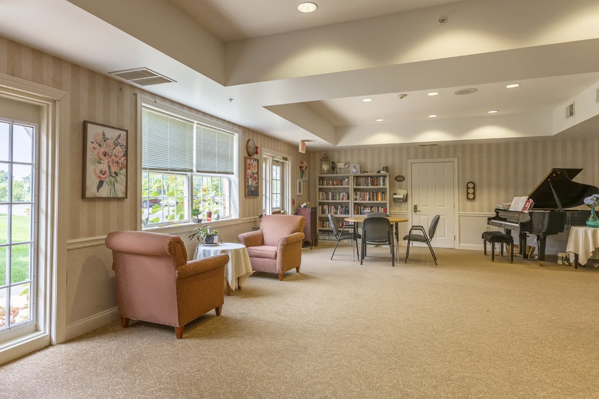 A cozy communal living room with comfortable seating, bookshelves, and natural lighting.