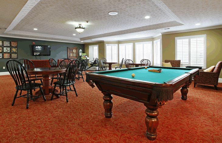 A recreation room featuring a pool table and a seating area with tables and chairs.