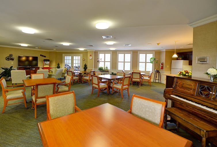 A spacious dining area with multiple tables and chairs, warmly lit by overhead lights.