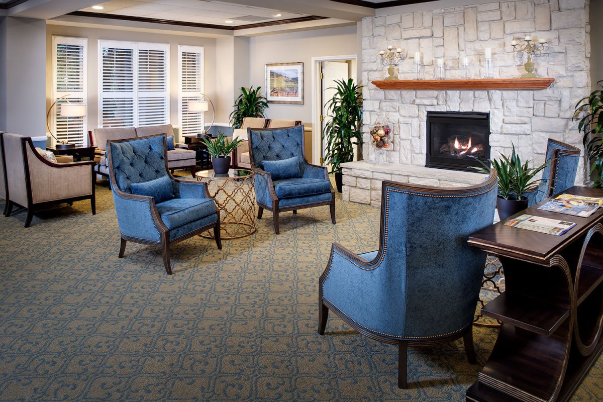 A cozy living room featuring blue chairs and a fireplace.