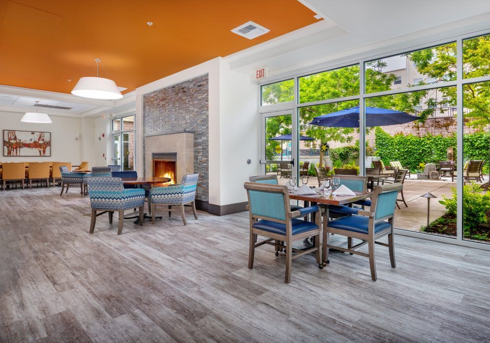 A cozy indoor dining area with a fireplace and large windows overlooking a patio.
