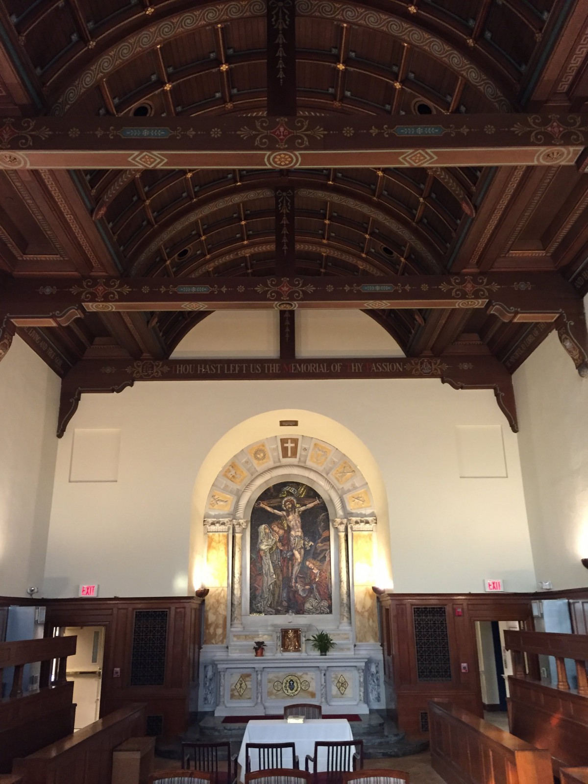 An interior view of a church featuring a wooden ceiling and an ornate altar.