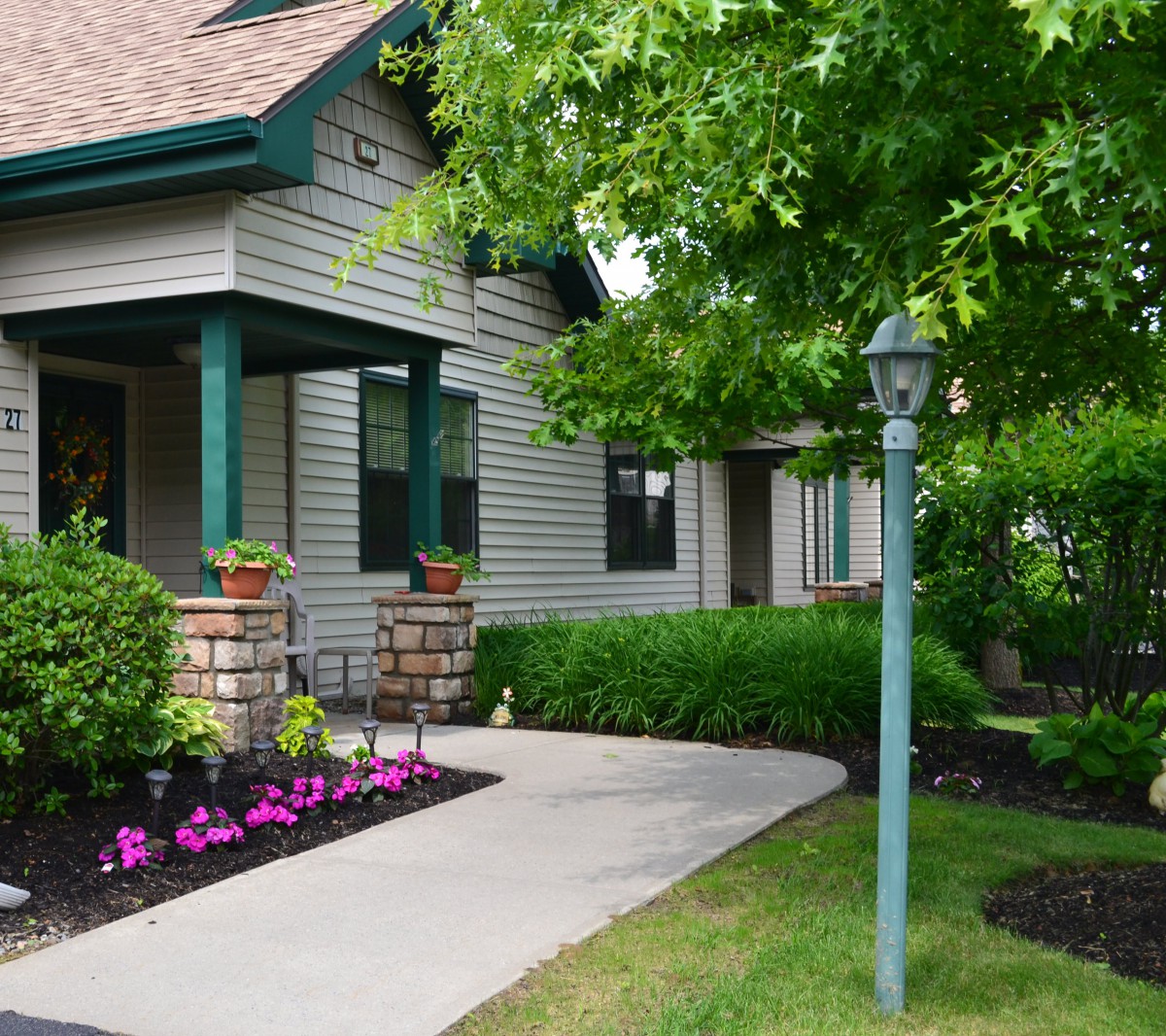 A charming house with a well-maintained garden, featuring a porch and a sidewalk lined with flowers.