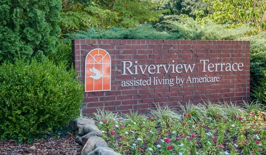 Sign for Riverview Terrace assisted living, surrounded by a garden.