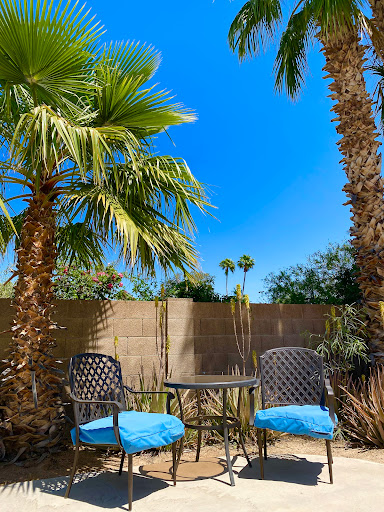 A serene patio setup under palm trees, perfect for relaxation on a sunny day.