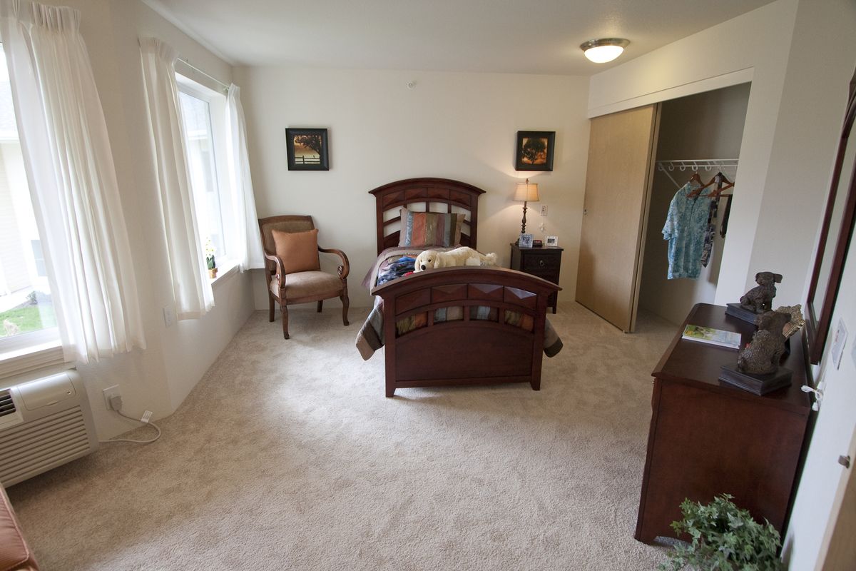 A cozy bedroom with a single bed, a chair by the window, and an open closet.
