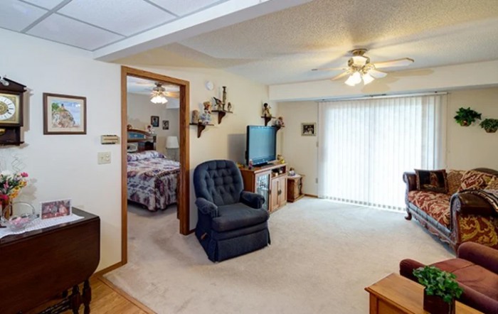 A cozy living room with an armchair, television, and ceiling fan.