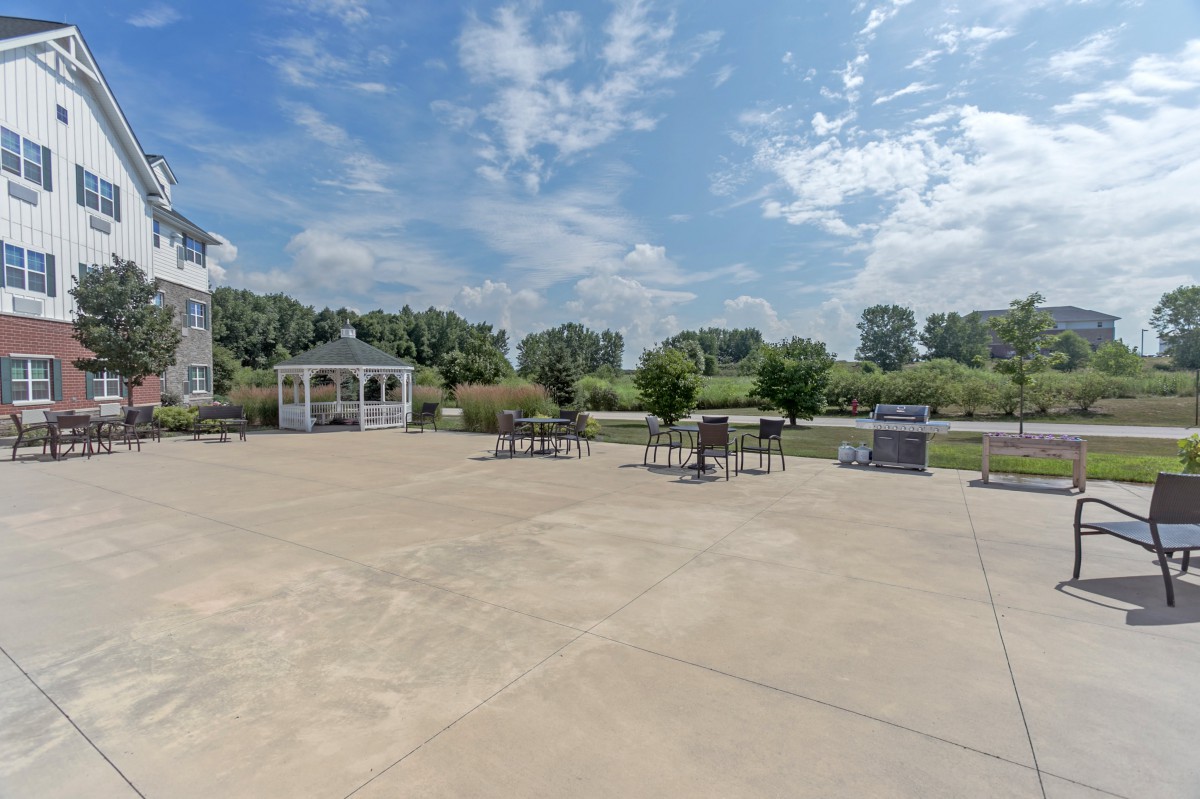 A spacious outdoor patio area with a gazebo, seating arrangements, and a scenic landscape under a partly cloudy sky.