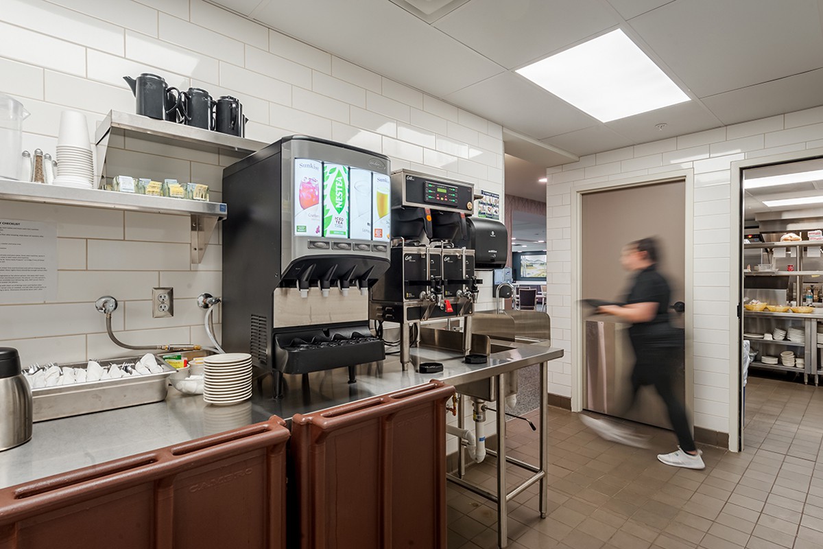 A busy restaurant kitchen with a soda machine and beverage station.