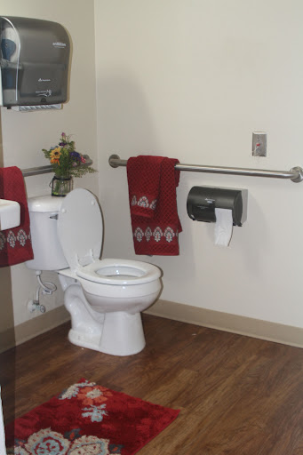A clean and simple restroom with a toilet, hand towels, and hygiene accessories.