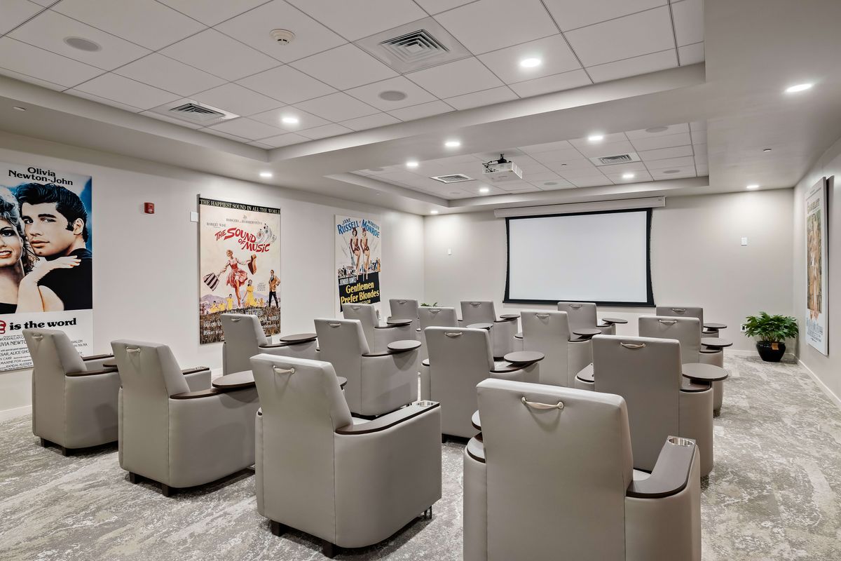 A cozy home theater with comfortable recliner seating and a large screen, flanked by movie-themed posters on the walls.