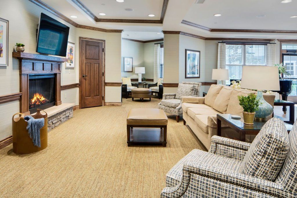 A spacious and elegantly furnished living room with a large TV, cozy sofas, and soft lighting.