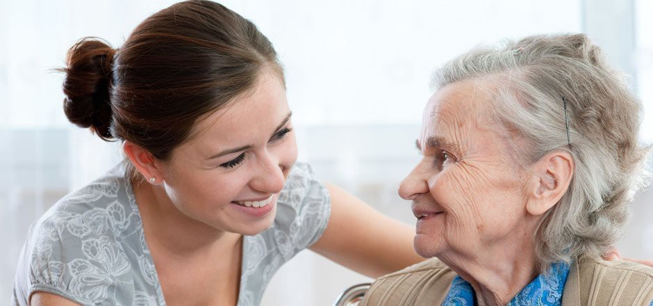 A young woman smiling at an elderly person, sharing a moment of connection.