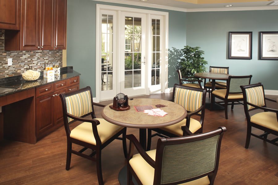 A modern dining room with a round table and upholstered chairs, featuring natural light from glass doors and elegant interior design.