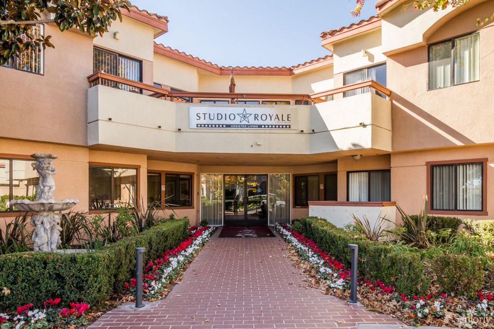 A welcoming entrance to a residential or commercial building, featuring well-maintained landscaping and colorful flowers.