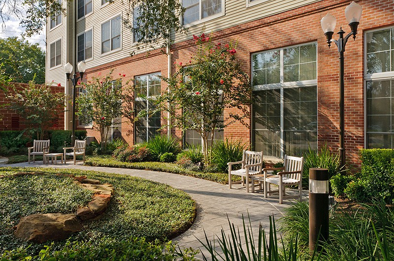 A beautifully landscaped courtyard with outdoor seating and lush greenery alongside a building.