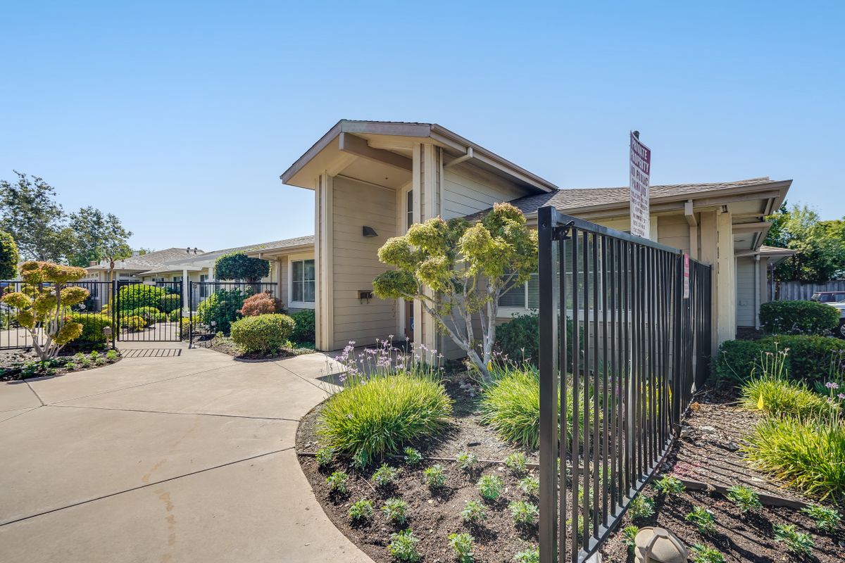 A well-maintained building with a landscaped garden and a black fence along the pathway.