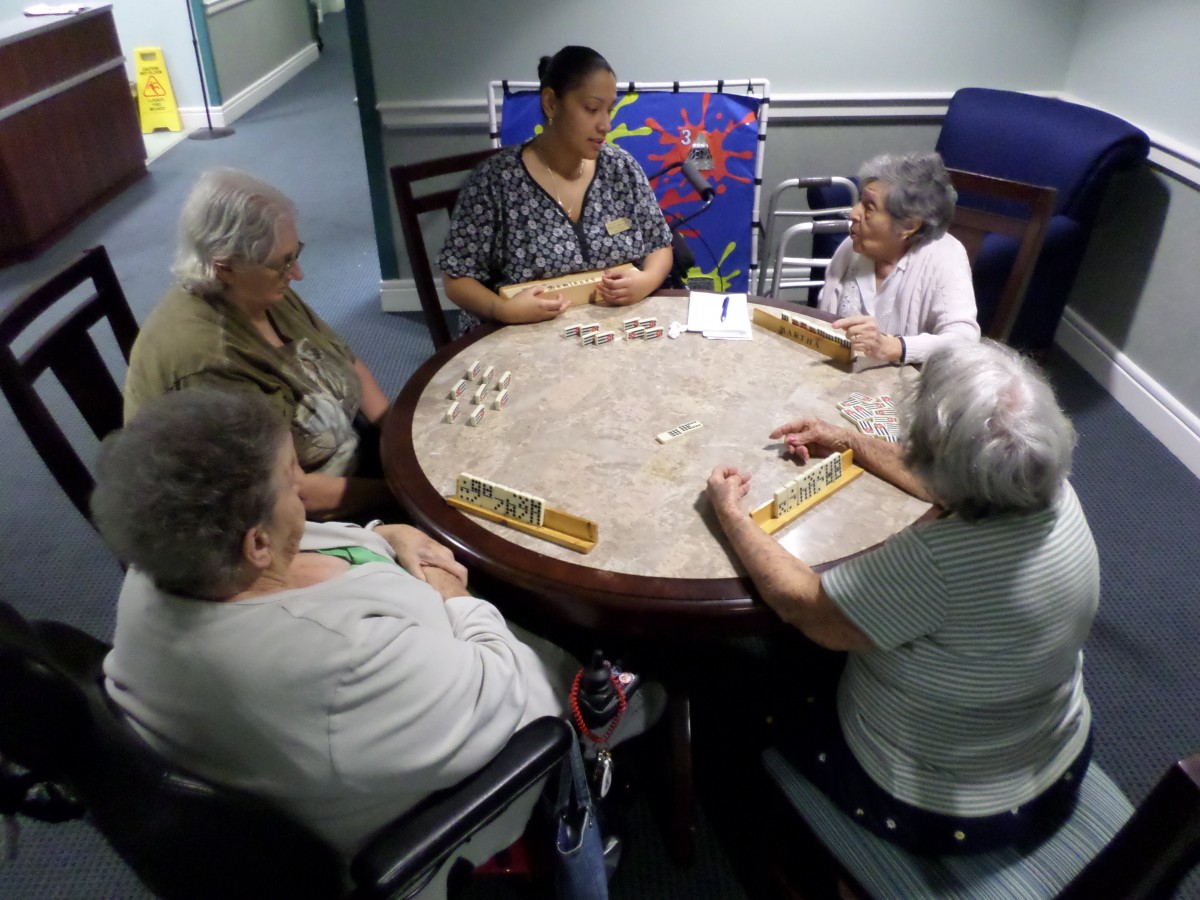 A group of seniors enjoys a board game together at a round table.