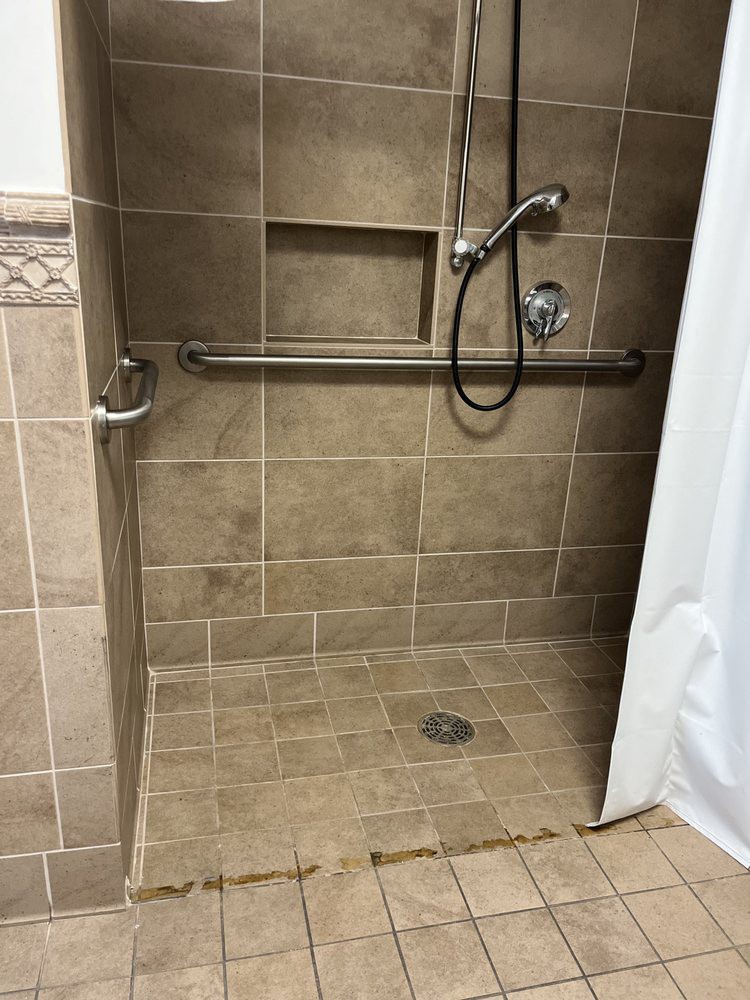 A tiled walk-in shower with a grab bar and handheld showerhead.