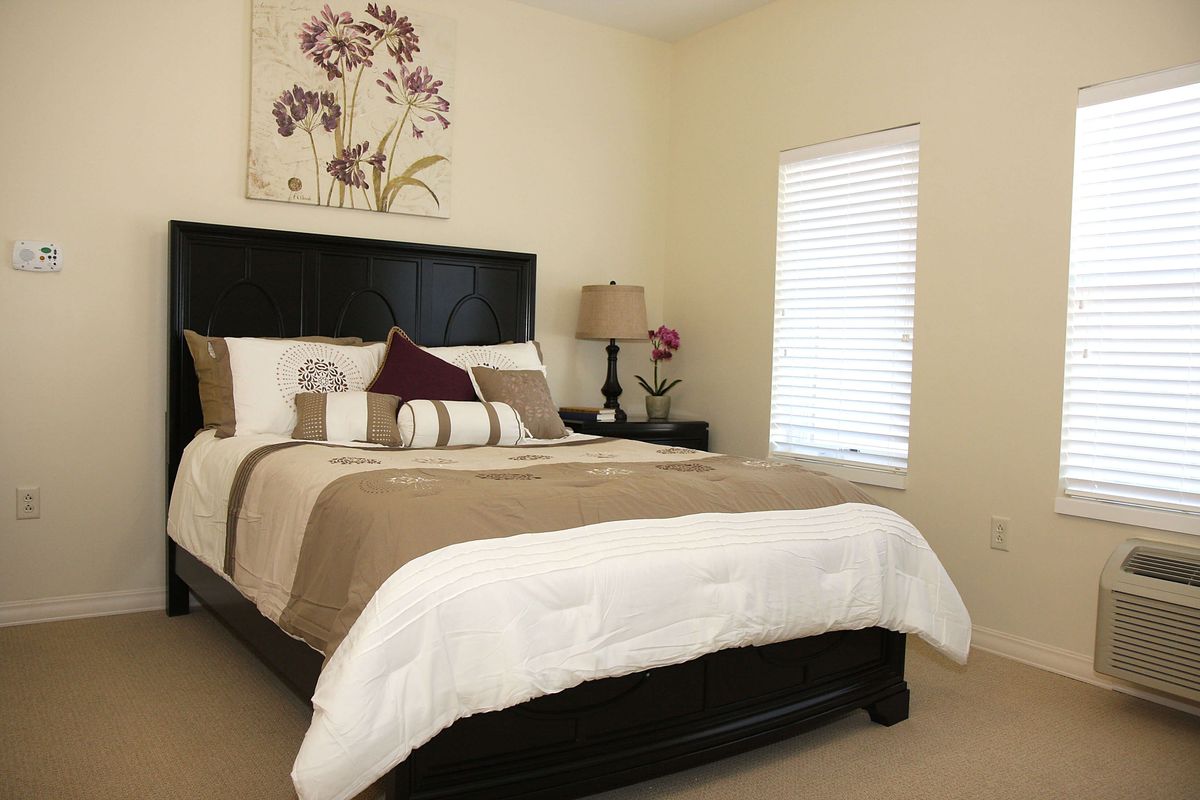 A cozy bedroom with a neatly made bed, soft lighting, and tasteful wall art.