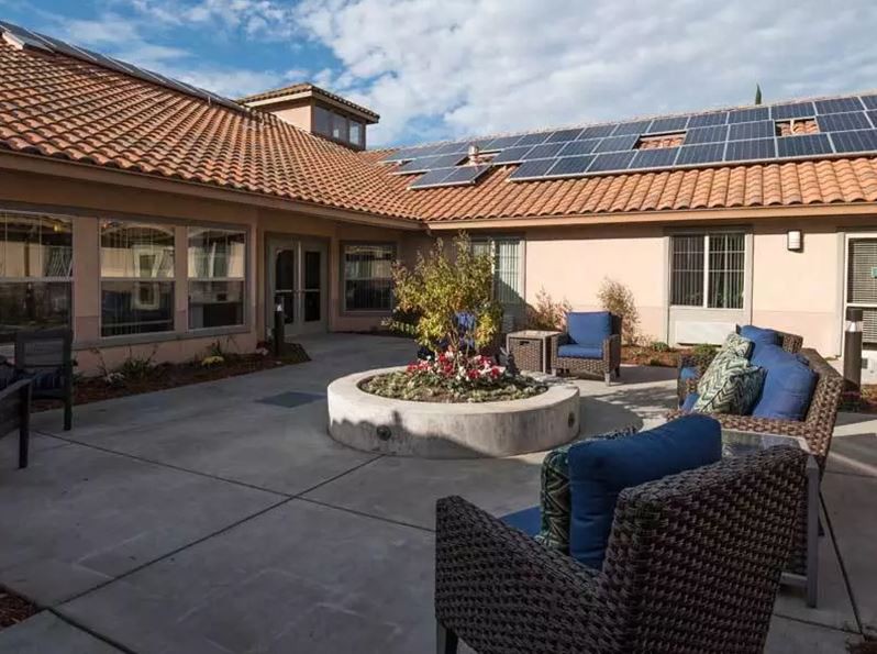 A sunny courtyard patio with seating and solar panels on the roof.