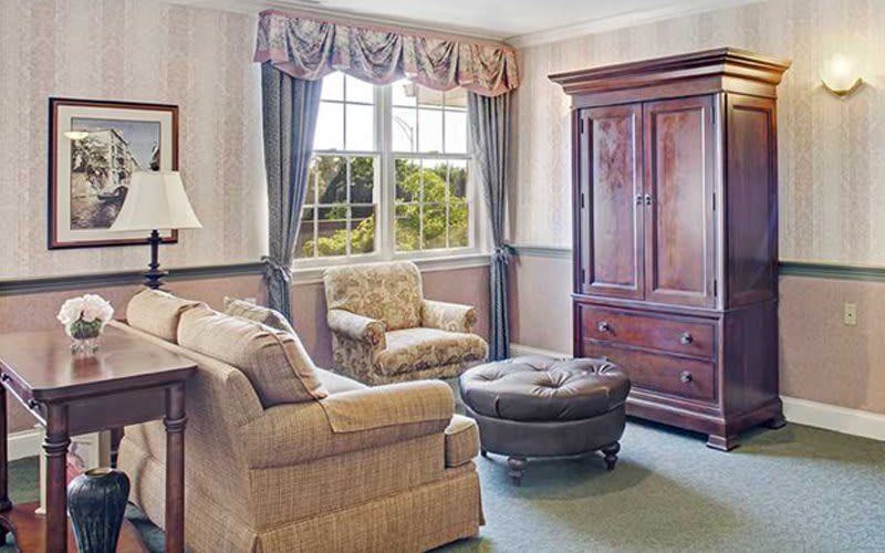 A cozy living room with a large window, comfortable armchairs, and elegant furnishings.