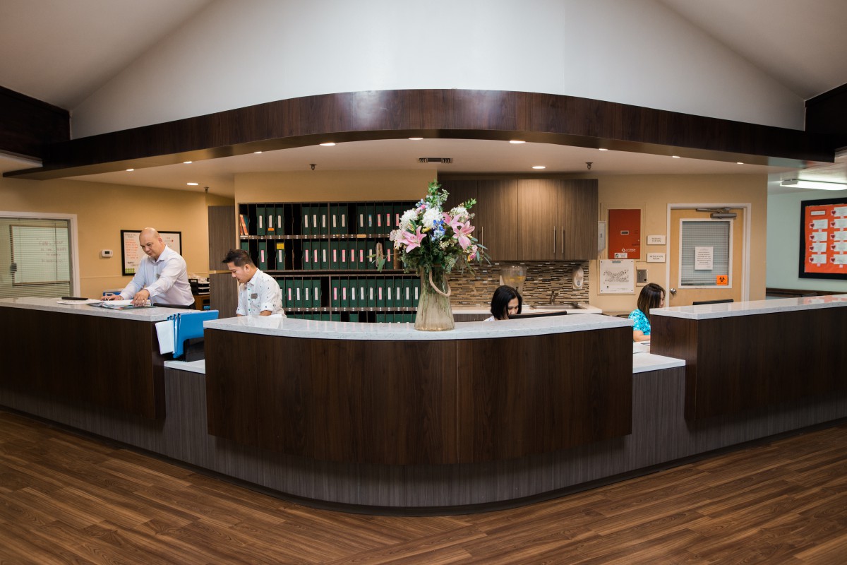 Reception desk area with people working and floral arrangement.
