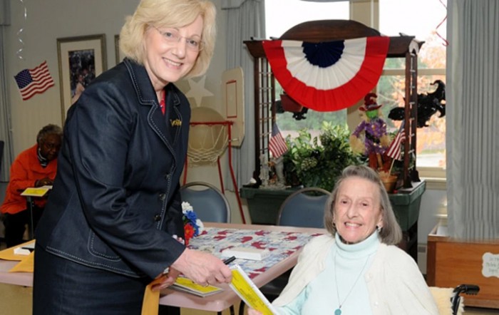Two women smiling and interacting at an event with patriotic decorations.