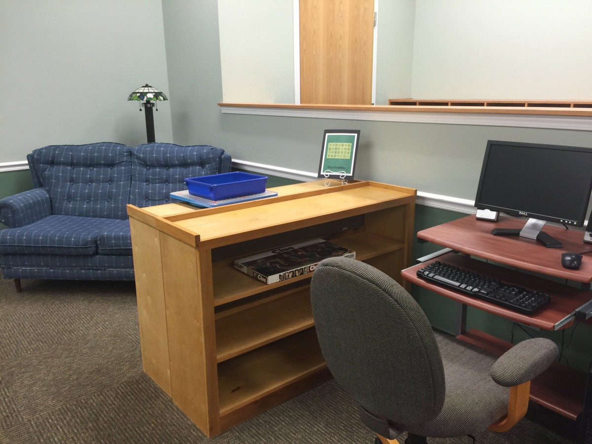 An office space featuring a desk with a computer, a chair, and a blue sofa.