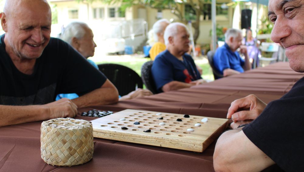 A group of elderly people playing a board game outdoors.