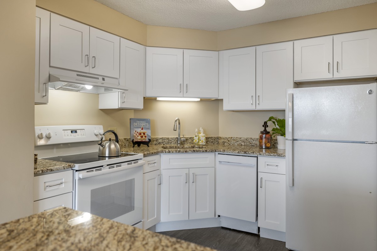 A modern kitchen with white cabinets and granite countertops.
